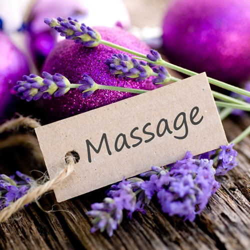 Fresh lavender sprigs beside a kraft paper tag reading Massage, on weathered wood